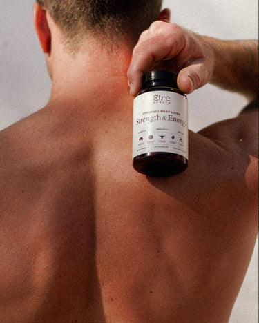 Person holding a bottle labeled 'Strength & Energy' against a plain background